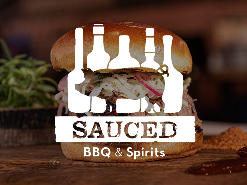 Decorative image of the Sauced BBQ and Spirits logo on a photo of a bbq sandwich.